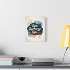 11 × 14 Rest Recharge Rise canvas displayed on a light wall above a console