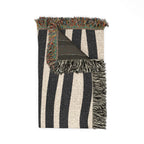 Folded abstract stripe blanket showing woven texture and fringe