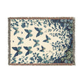 Blue butterflies above a botanical garden border on a cream woven blanket