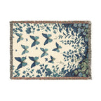 Blue butterflies above a botanical garden border on a cream woven blanket