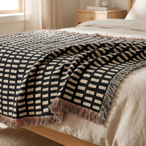 Black and cream hand-drawn grid woven blanket styled on a neutral bed