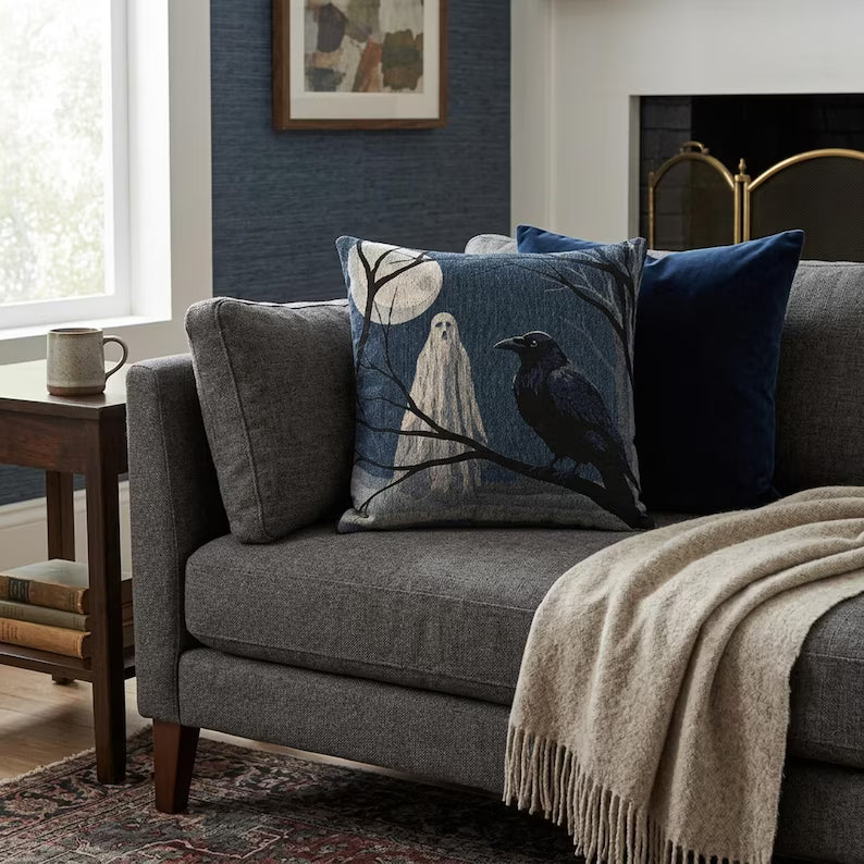 Ghost and raven woven Halloween pillow styled on a gray living room sofa