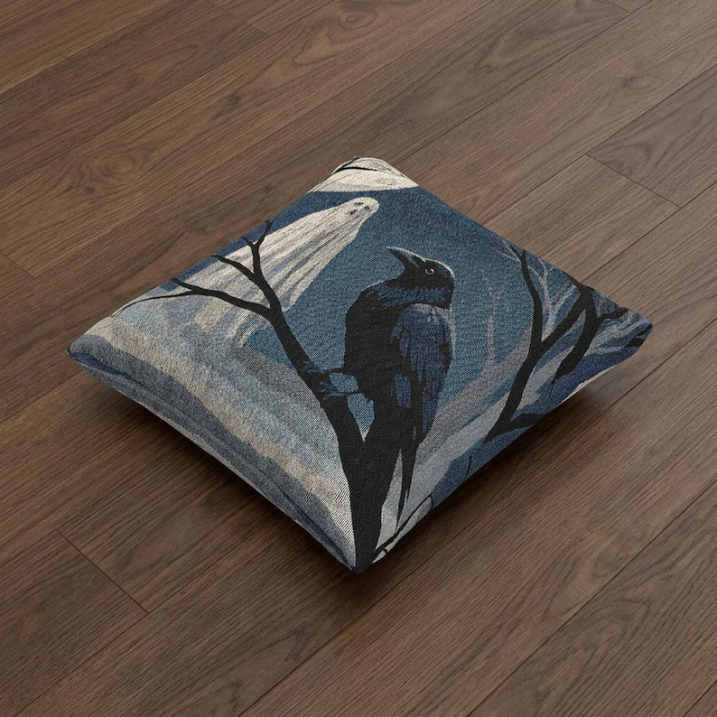 Ghost and raven woven Halloween pillow shown at an angle on a wood floor