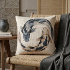Japandi koi fish woven pillow with indigo and tan circular design on a woven chair