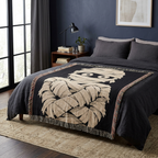 Black and cream mummy throw blanket styled across a bed