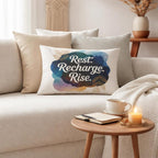 Rest Recharge Rise affirmation lumbar pillow styled on a cream sofa